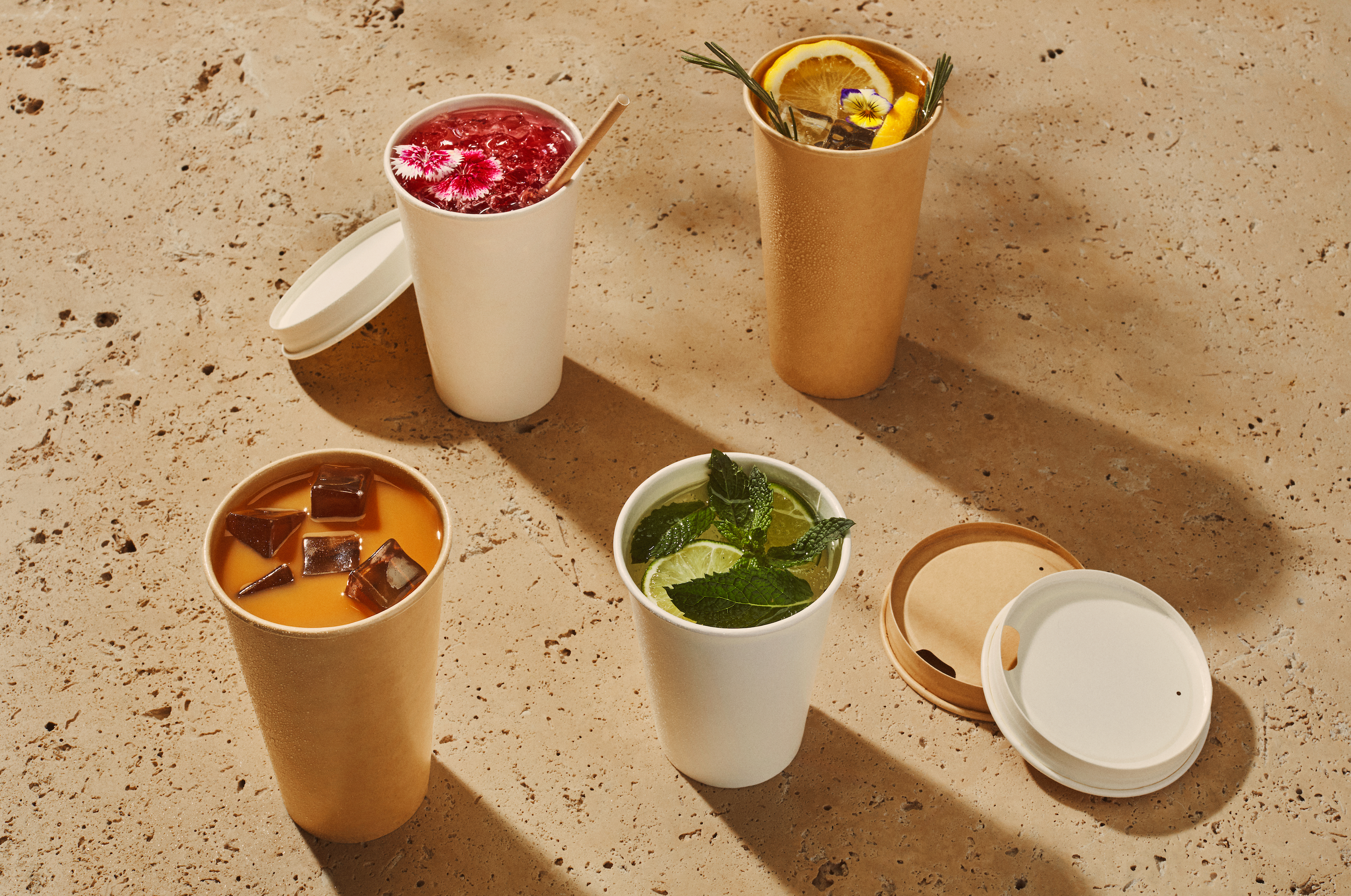 The image shows several bamboo takeaway cups filled with dark coffee, arranged on a blue background.