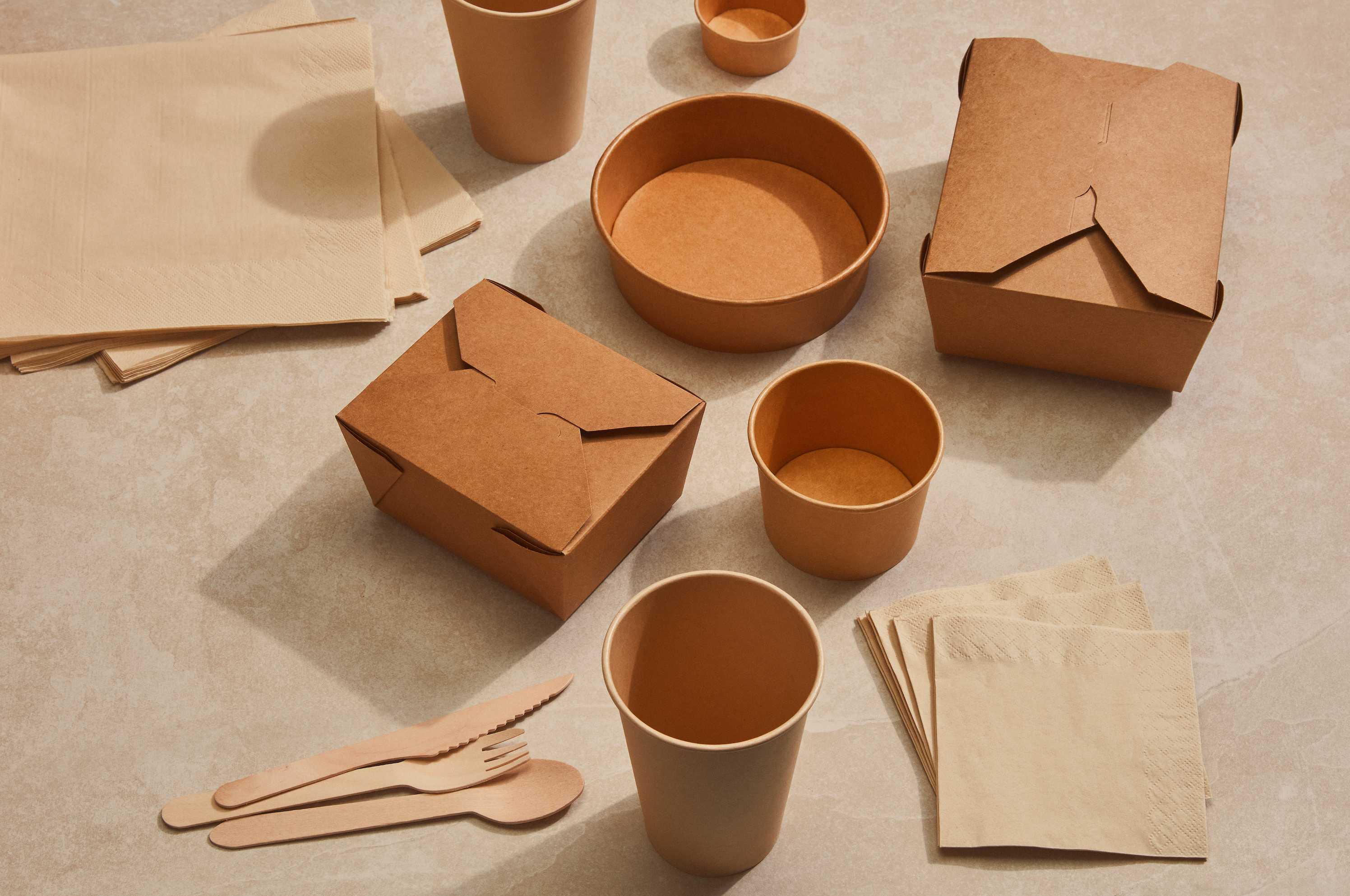 A woman's hand holding a sustainable take-out Kraft paper bag.