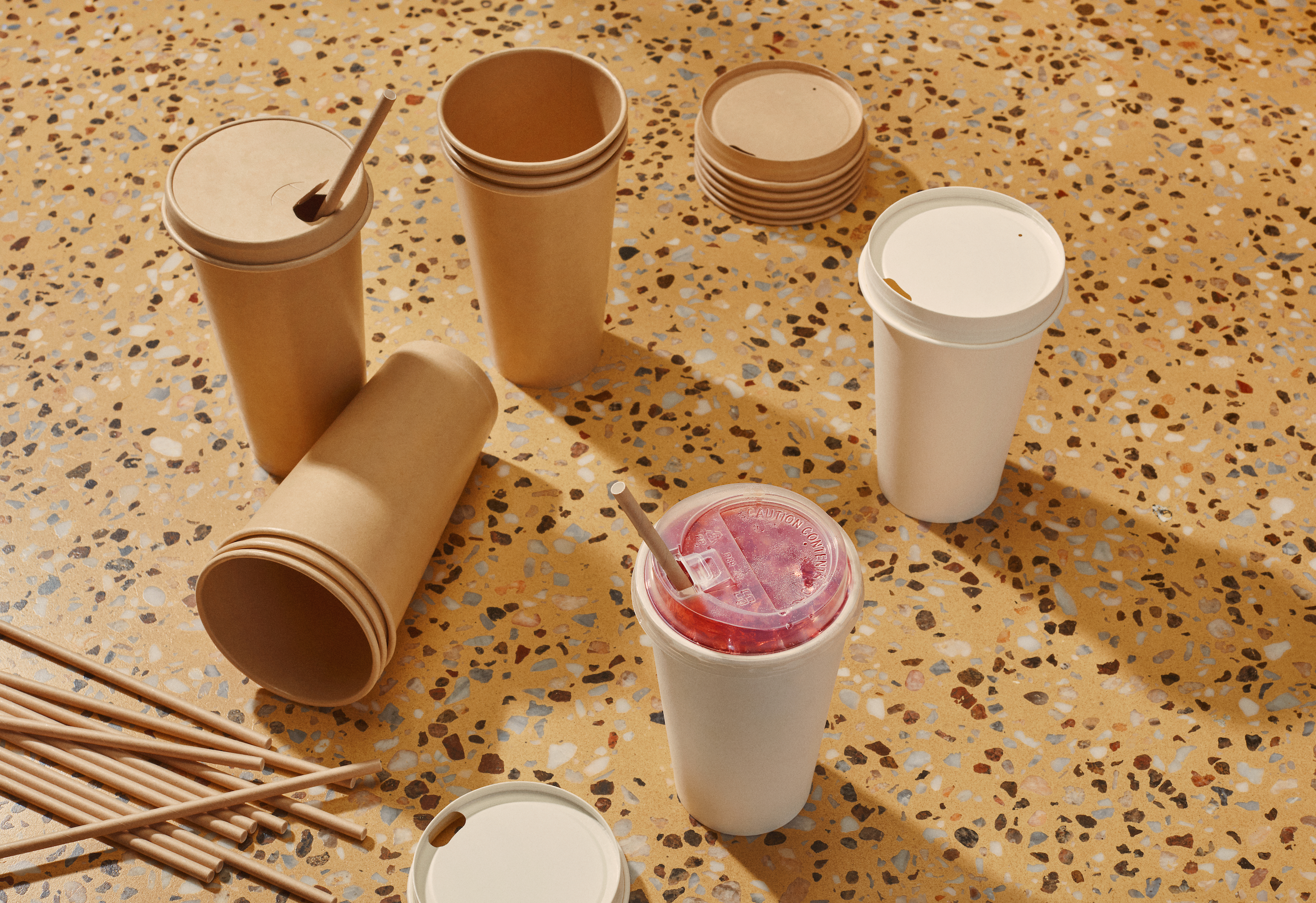 The image shows several bamboo disposable cups, arranged on a blue background, suggesting a theme of sustainable packaging solutions.