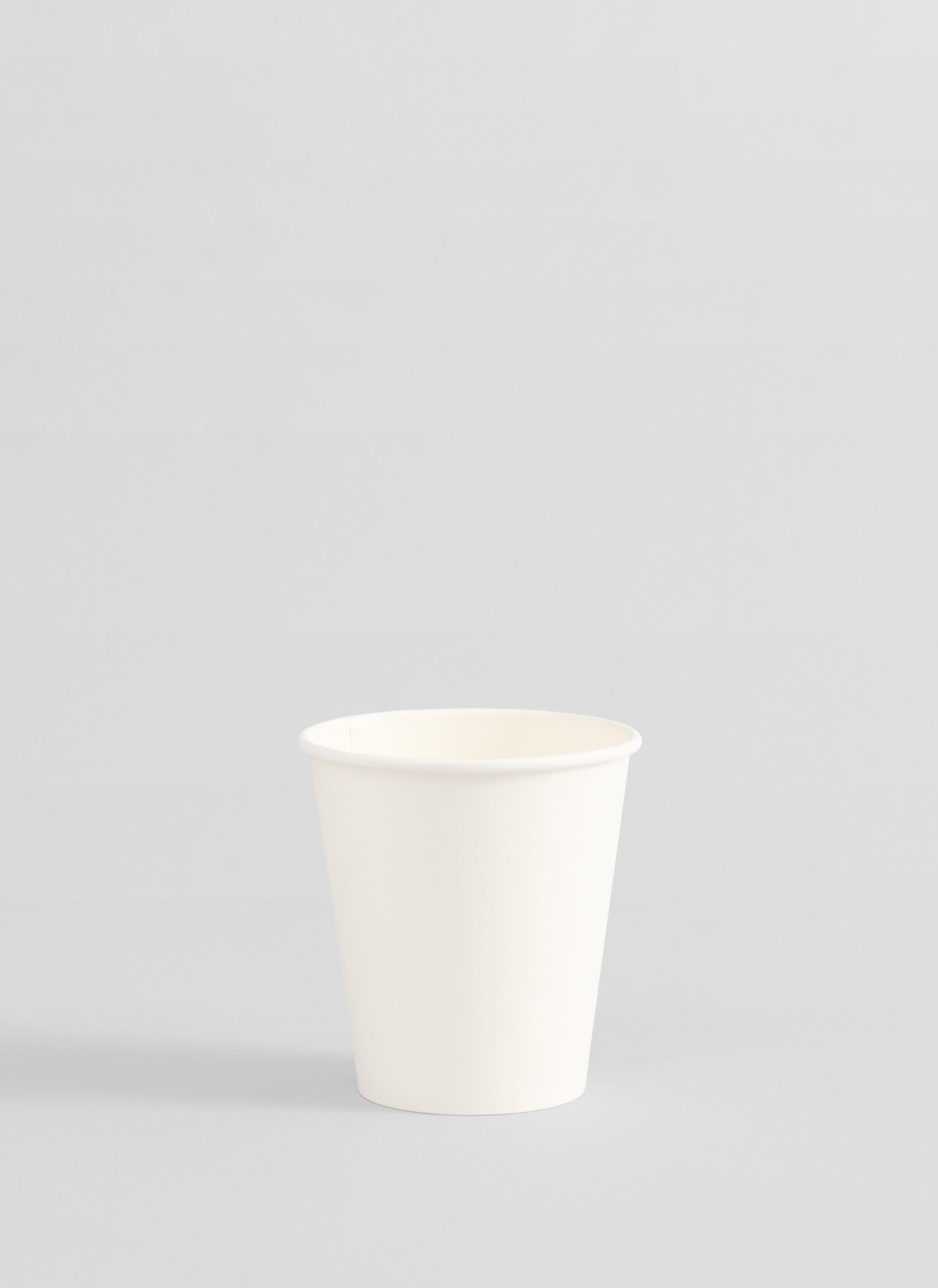 A plain white paper cup centered against a light gray studio background.