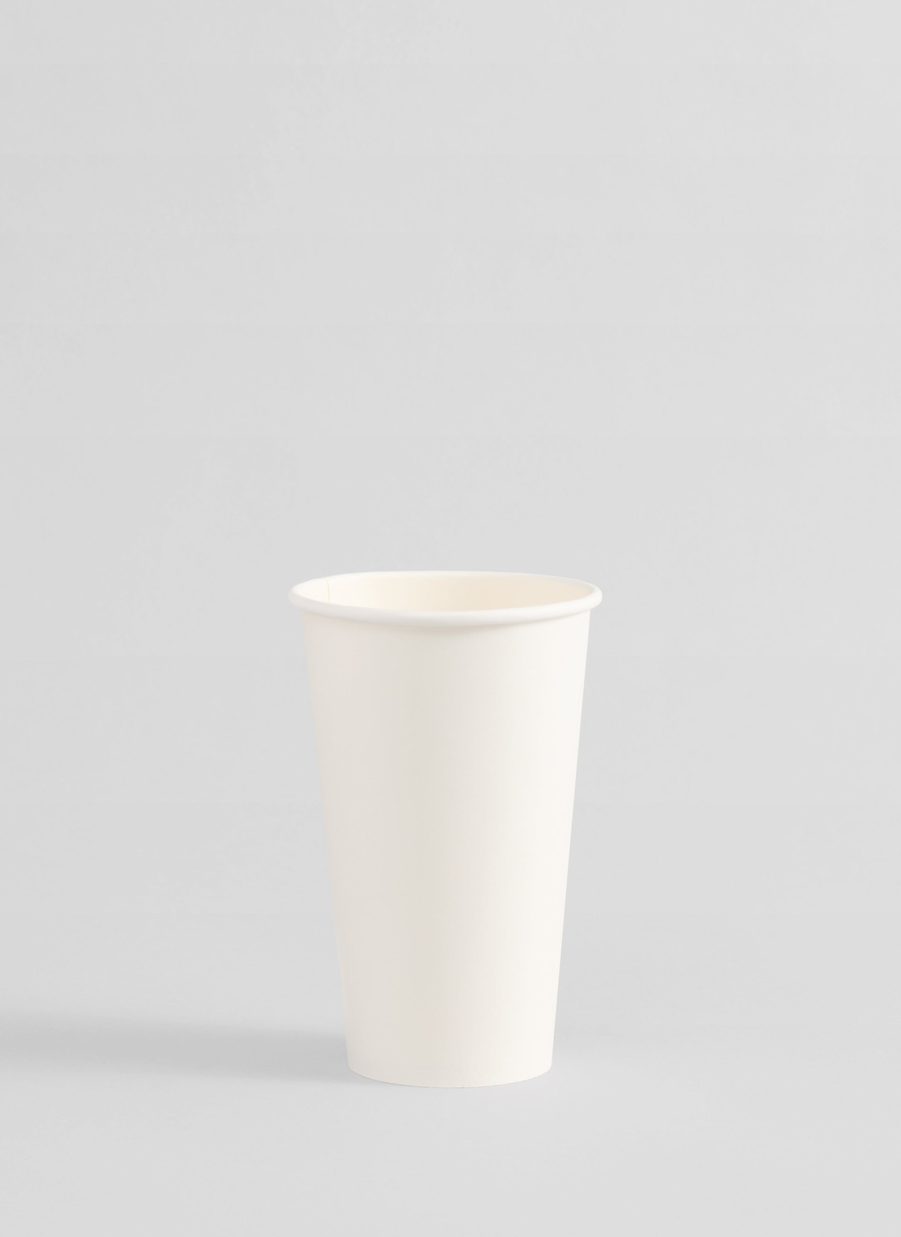 A plain white paper cup centered on a light gray studio background.