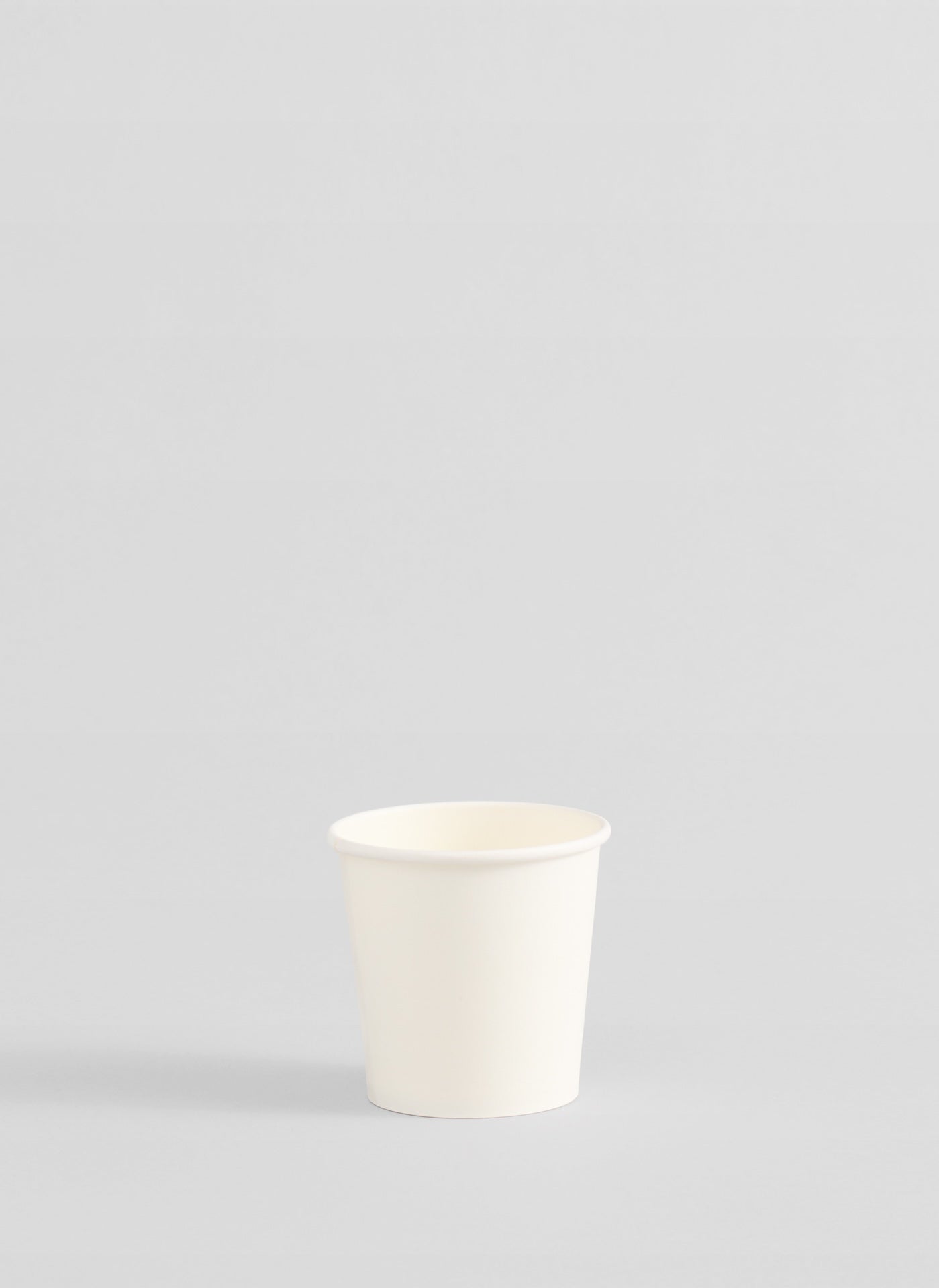A single white paper cup centered on a light gray background.