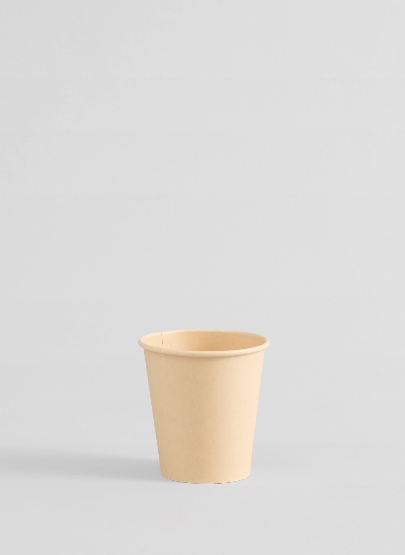 Compostable beige bamboo paper cup on a light gray background